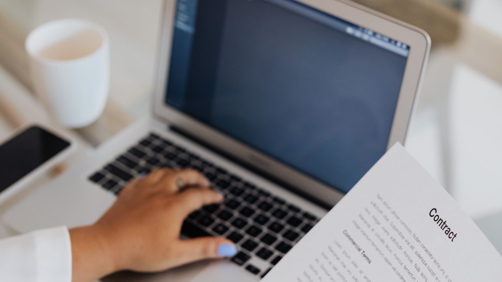 Professional reviewing legal documents while working on a laptop