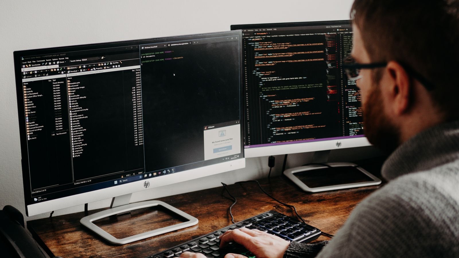 Software developer working with code across multiple computer monitors