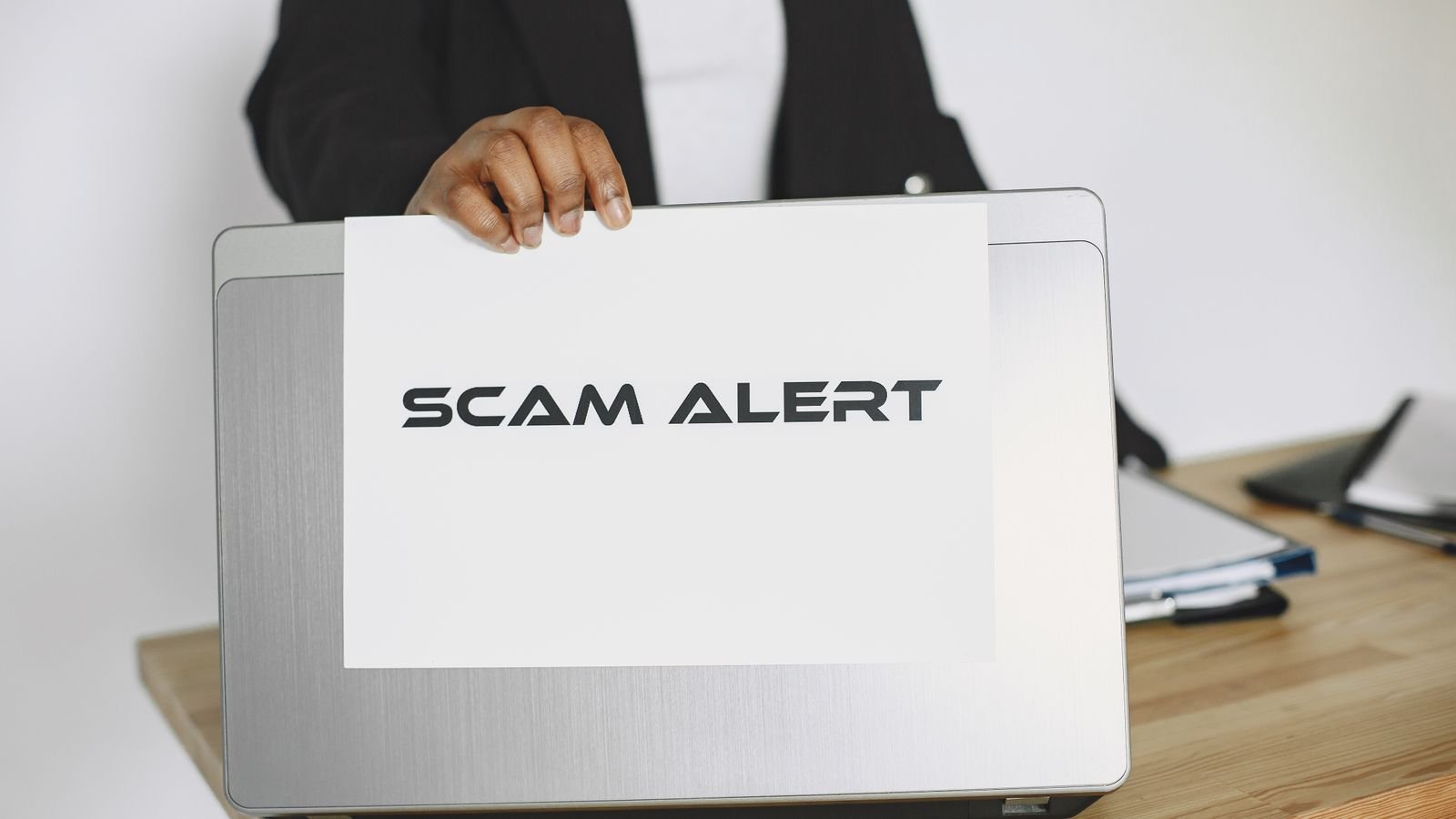 Business professional reviewing an online scam warning beside a laptop